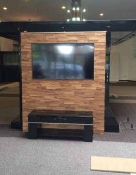 Realizace obkladu z exotického dřeva za televizí v obchodních prostorech