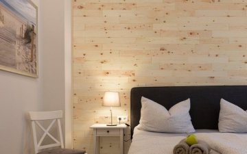 Realizace dřevěného obkladu z borovice na stěně v ložnici