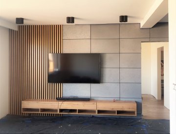 Realizace obkladu z akustických panelů s dubovými lamelami na stěně v obýváku